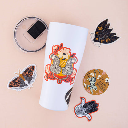 Golden moth clear vinyl sticker with patterned black and rust-colored wings, shown among other stickers