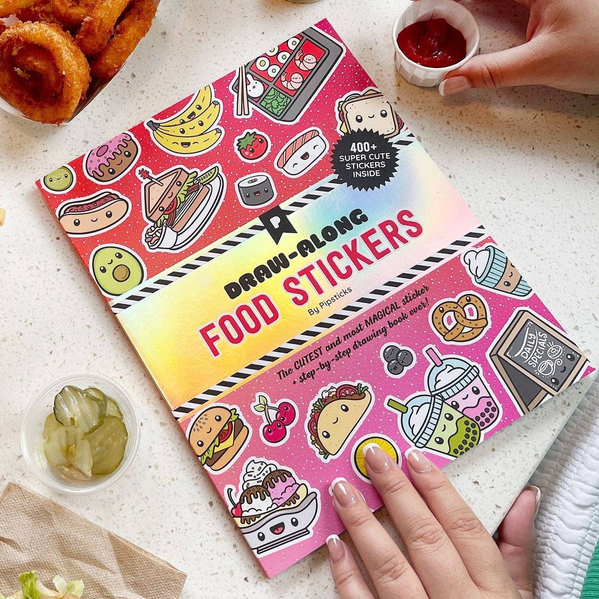 Food sticker book cover with colorful drink and dessert stickers and hands holding it