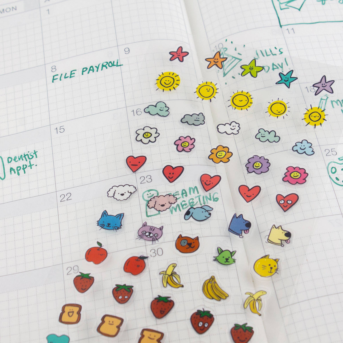 Clear planner sticker sheet on calendar with hearts, clouds, cats, fruit, and bananas