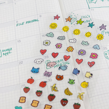 Clear planner sticker sheet on calendar with hearts, clouds, cats, fruit, and bananas