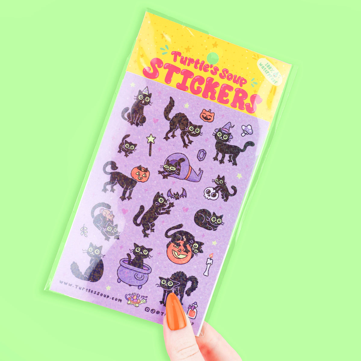 Halloween sticker sheet with black cats and jack-o'-lanterns; hand holding sheet