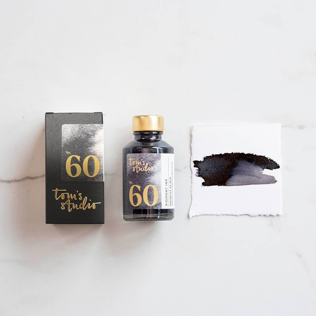 Fountain pen ink bottle with box and black pigment ink swatch on paper