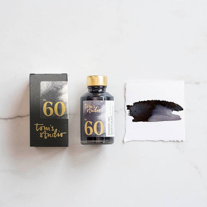 Fountain pen ink bottle with box and black pigment ink swatch on paper