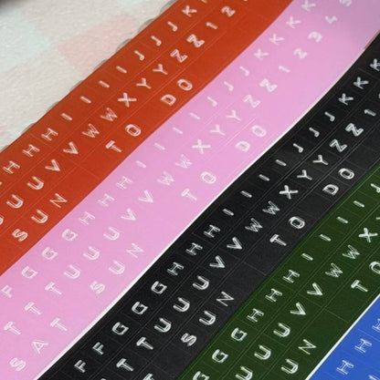 Embossed letter kiss-cut PET tape strips in multiple colors, aligned on surface