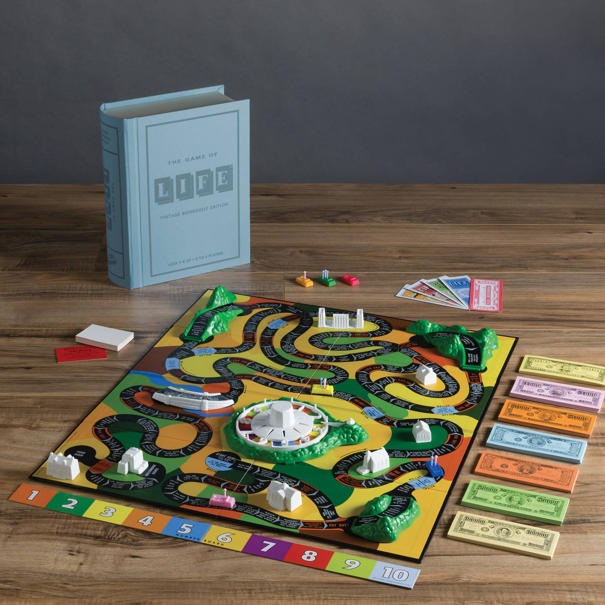 Board game setup with green-and-yellow path board, money, and standing box