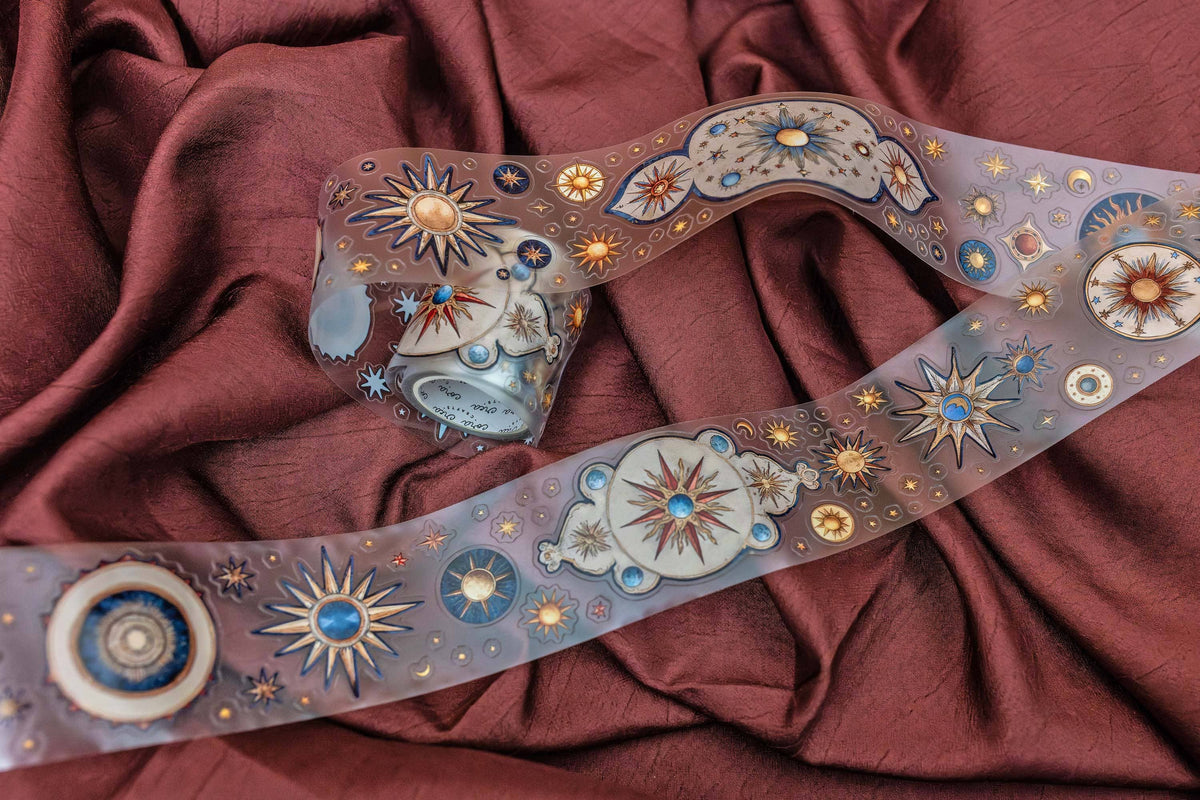 Astronomy transparent tape strip with large sun and blue circular planets, gold stars