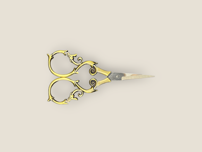 Ornate gold-toned scissors laid sideways with curled filigree handles