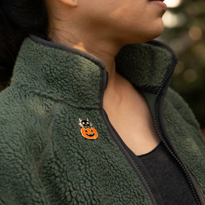 Halloween cat enamel pin attached to dark green fleece jacket near the collar