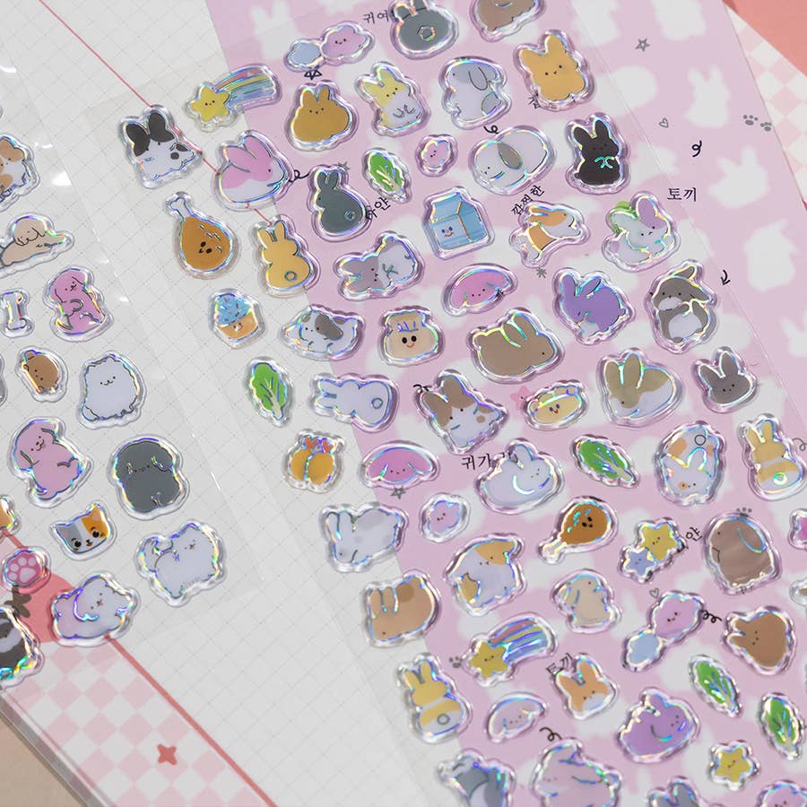 Close-up of pink-themed holographic cat stickers with ears, hearts, and small accessories.