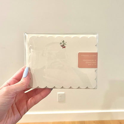 Cream scalloped note card in clear sleeve with small strawberry emblem