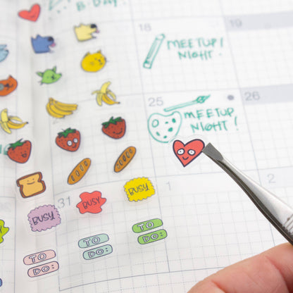 Clear planner stickers with dates, pencil notes, meeting text, and cat and banana icons