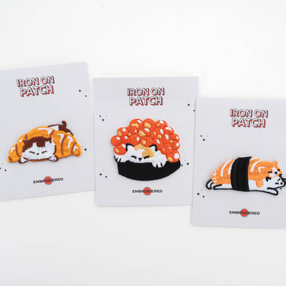 Iron-on cat food patch set cards with three embroidered designs: sleeping croissant, roe, and salmon sushi
