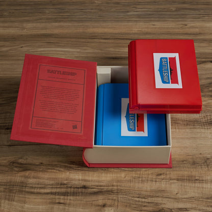 Open game set with red book lid, blue tray, and instruction pages for Battleship