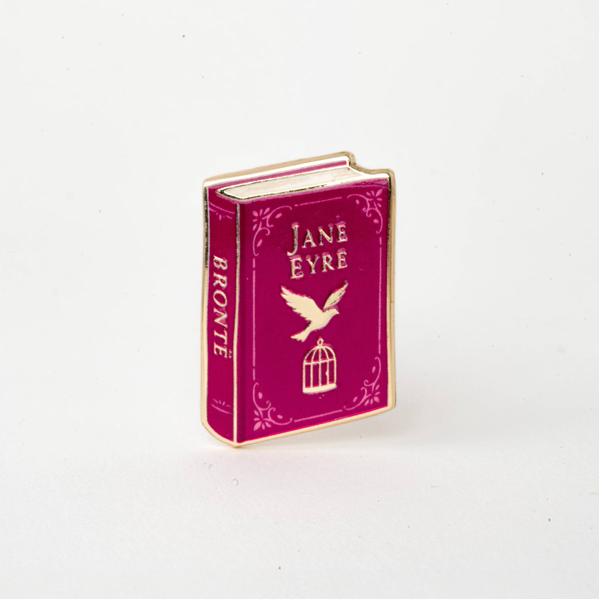 Maroon enamel book pin reading Jane Eyre, with bird and lantern cage icons, gold edges
