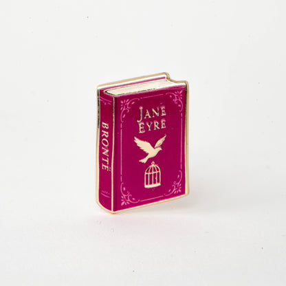 Maroon enamel book pin reading Jane Eyre, with bird and lantern cage icons, gold edges