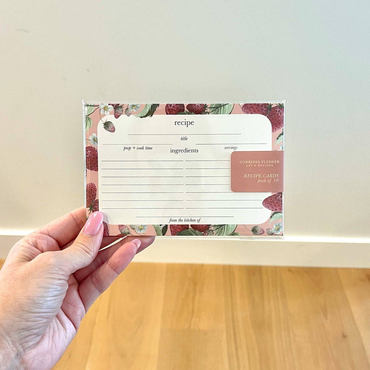 Watercolor strawberry recipe card with recipe and ingredients lines, held in hand