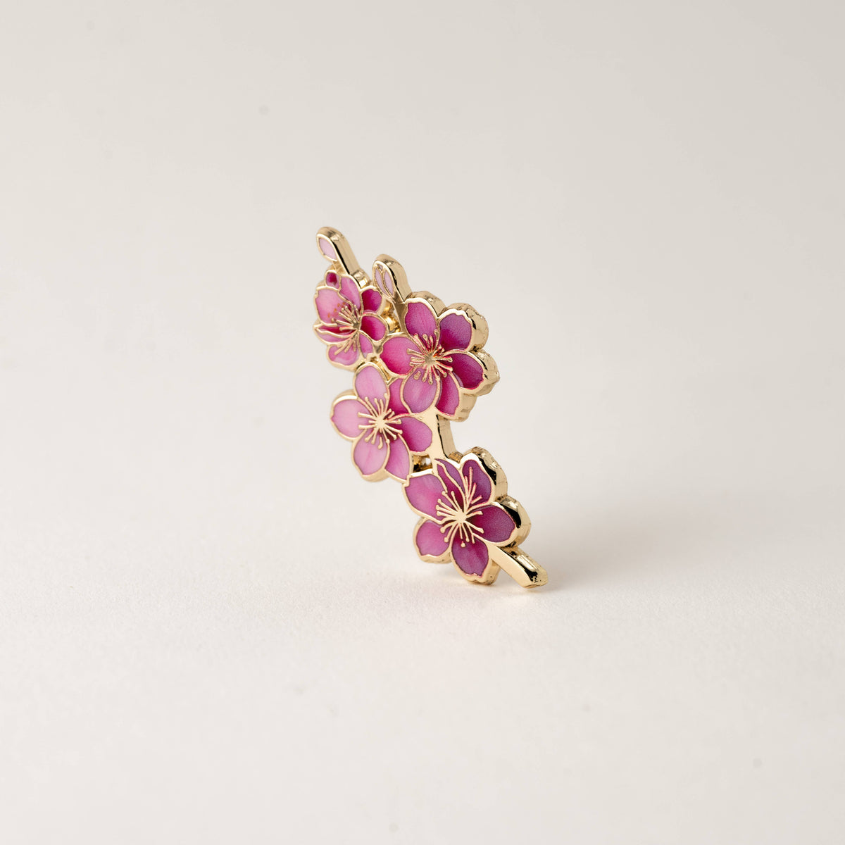 Pink cherry blossom enamel pin with gold-tone accents, side view