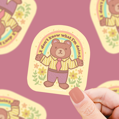 Brown bear vinyl sticker with yellow plaid shirt and flowers, round badge style