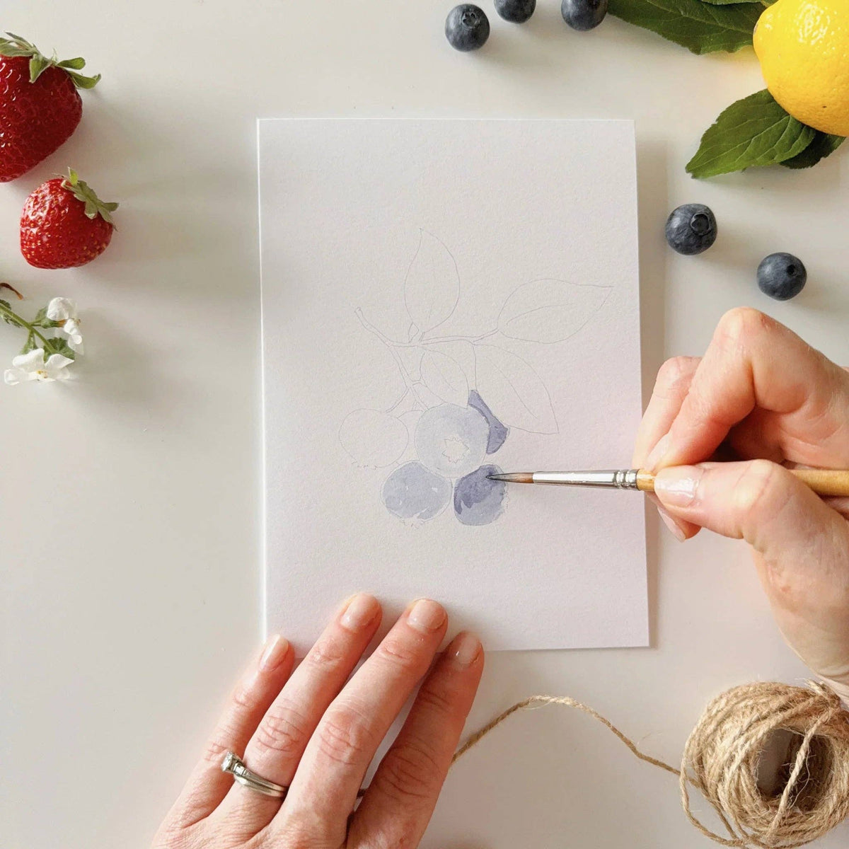 Paintable watercolor notecard with blue berry wash; hand painting details with brush.