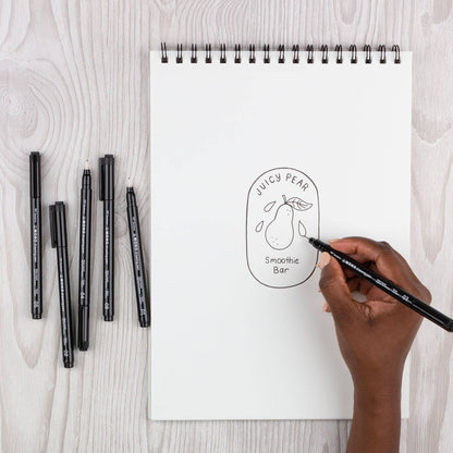 Black fine-tip drawing pen in hand, sketching a pear outline on a blank page