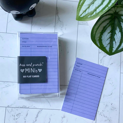 Purple library card notecard beside a clear case of matching cards