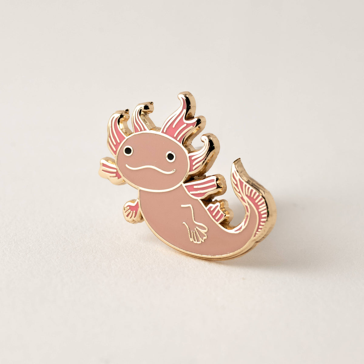Pink axolotl enamel lapel pin with gold border, curled tail and raised fins