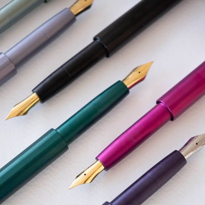 Pocket fountain pens in green, magenta, purple, and black with gold nibs.