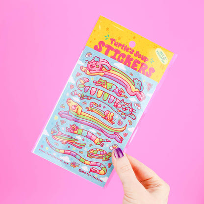 Hand holding a colorful glitter animal sticker sheet with “Sticker…” title