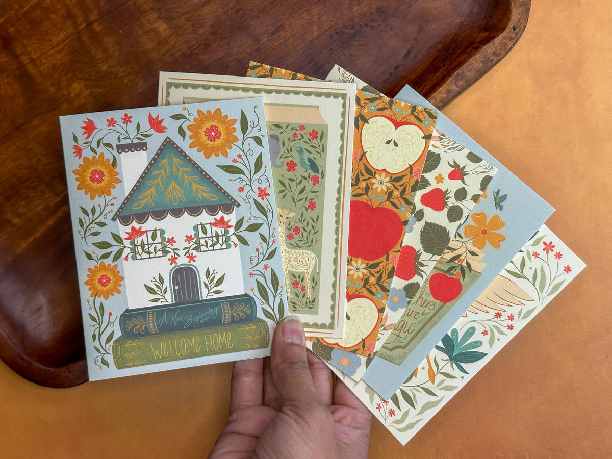 Folk-art housewarming greeting card with a floral cottage illustration