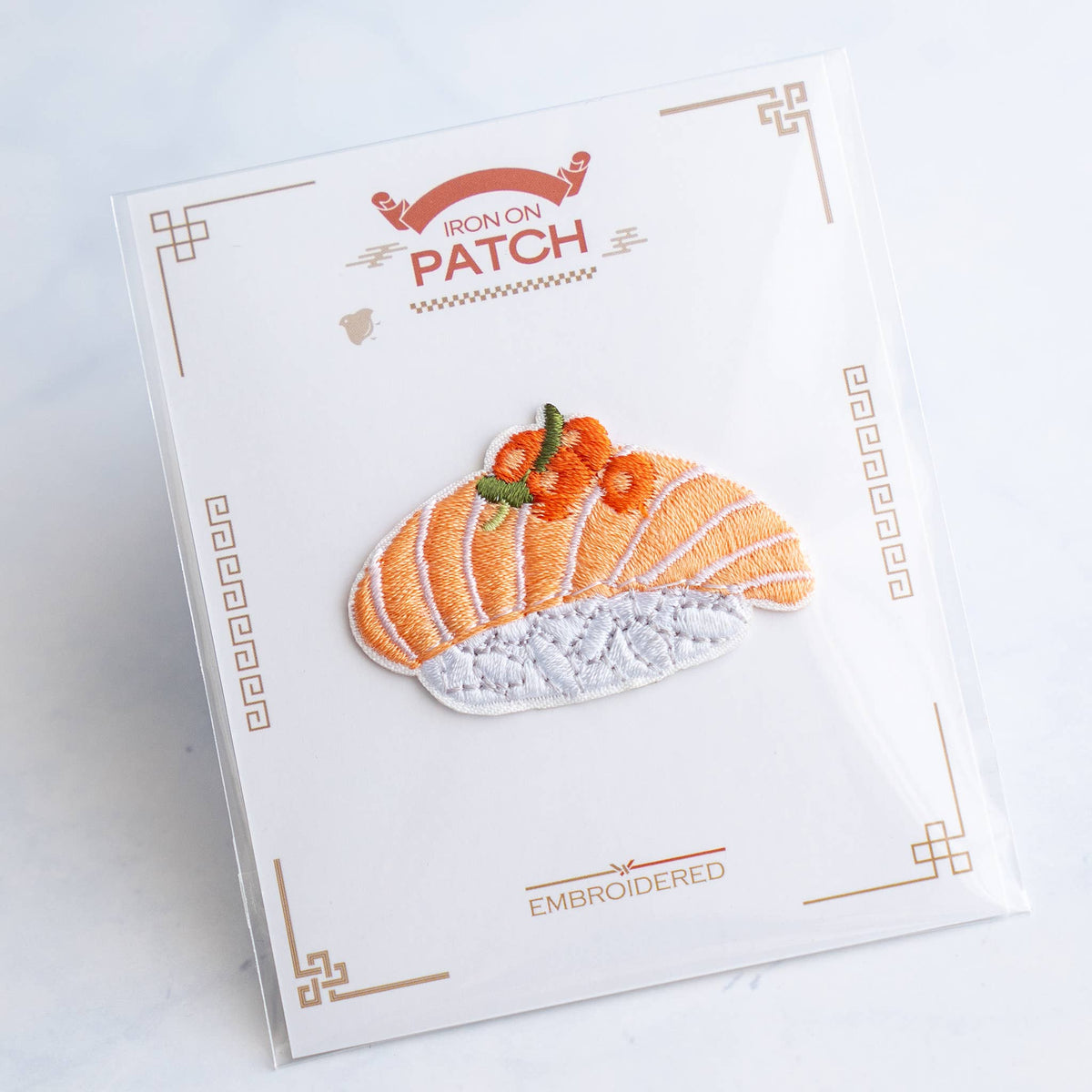 Salmon nigiri embroidered iron-on patch on card, with white base and orange stripes