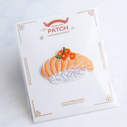 Salmon nigiri embroidered iron-on patch on card, with white base and orange stripes