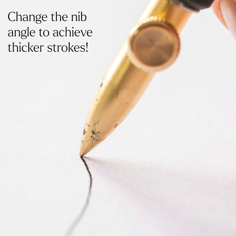 Gold dip pen nib creating a thick ink line on paper