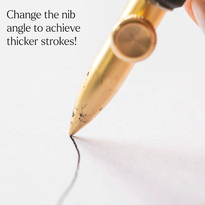 Gold dip pen nib creating a thick ink line on paper