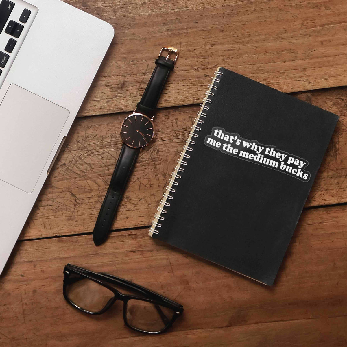 Funny quote sticker on black notebook cover: 'that's why they pay me the medium bucks'