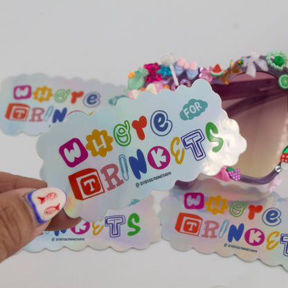 Holographic vinyl sticker with 'Whore for Trinkets' lettering and cloud outline, held