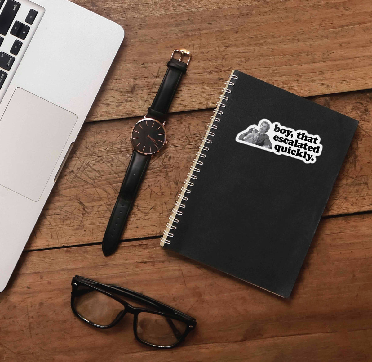 Boy escalated quickly quote sticker on black notebook with pen and glasses