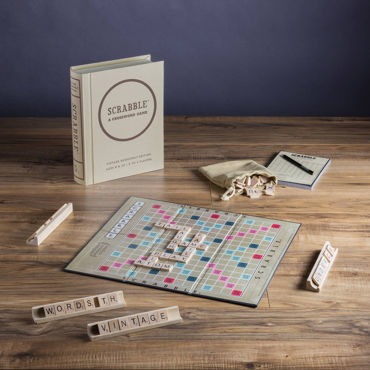 Scrabble board game set with booklet, letter tiles, and cloth bag on wood table