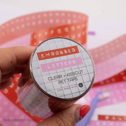 Embossed letters PET tape roll label reading Clear + kisscut PET tape