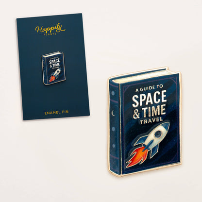 Enamel book pin with “A Guide to Space & Time Travel” book cover on card.