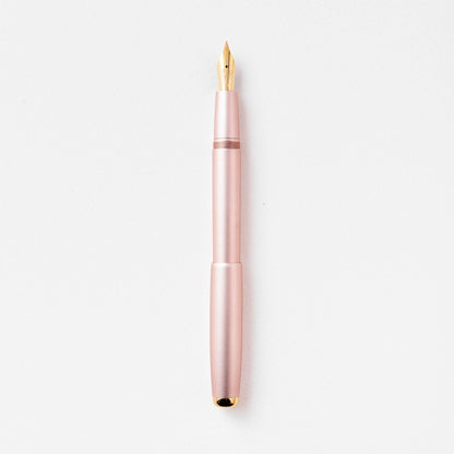 Rose pink fountain pen with gold nib, shown upright close-up