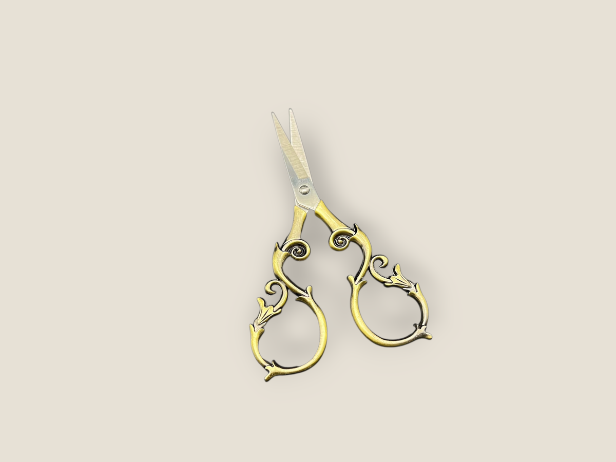 Ornate gold-toned scissors with curled handles and pointed blades