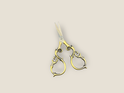 Ornate gold-toned scissors with curled handles and pointed blades