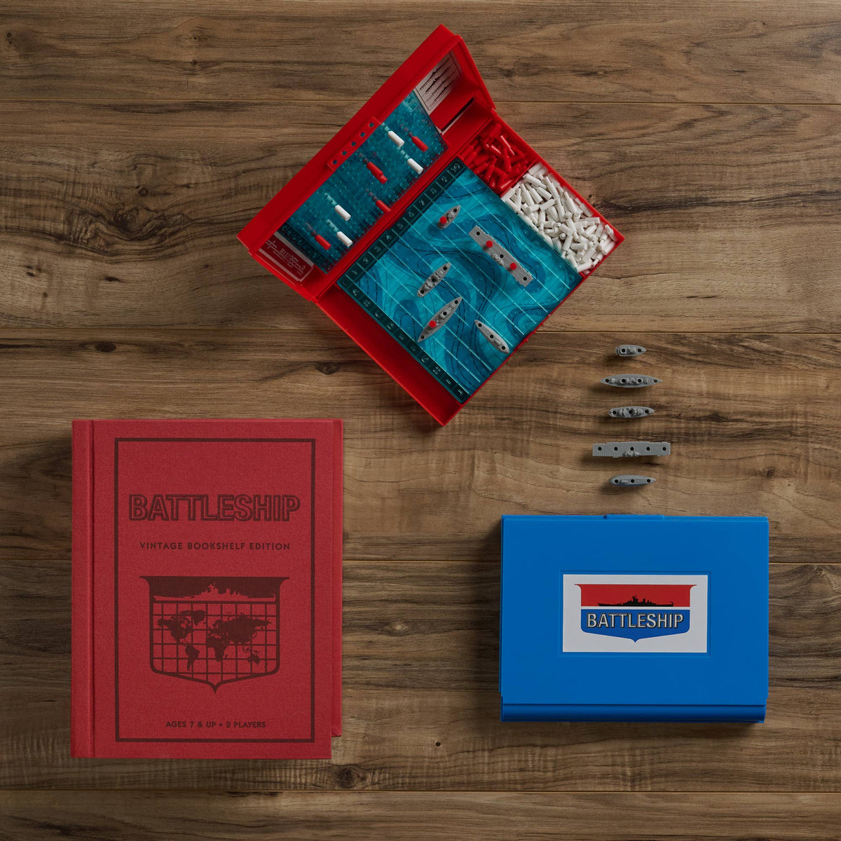 Battleship set with red and blue boxes, blue board, and scattered metal ship pieces