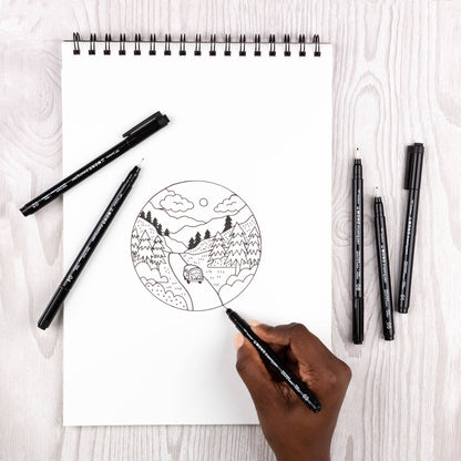 Set of black fine-tip drawing pens beside a spiral sketch on a white pad