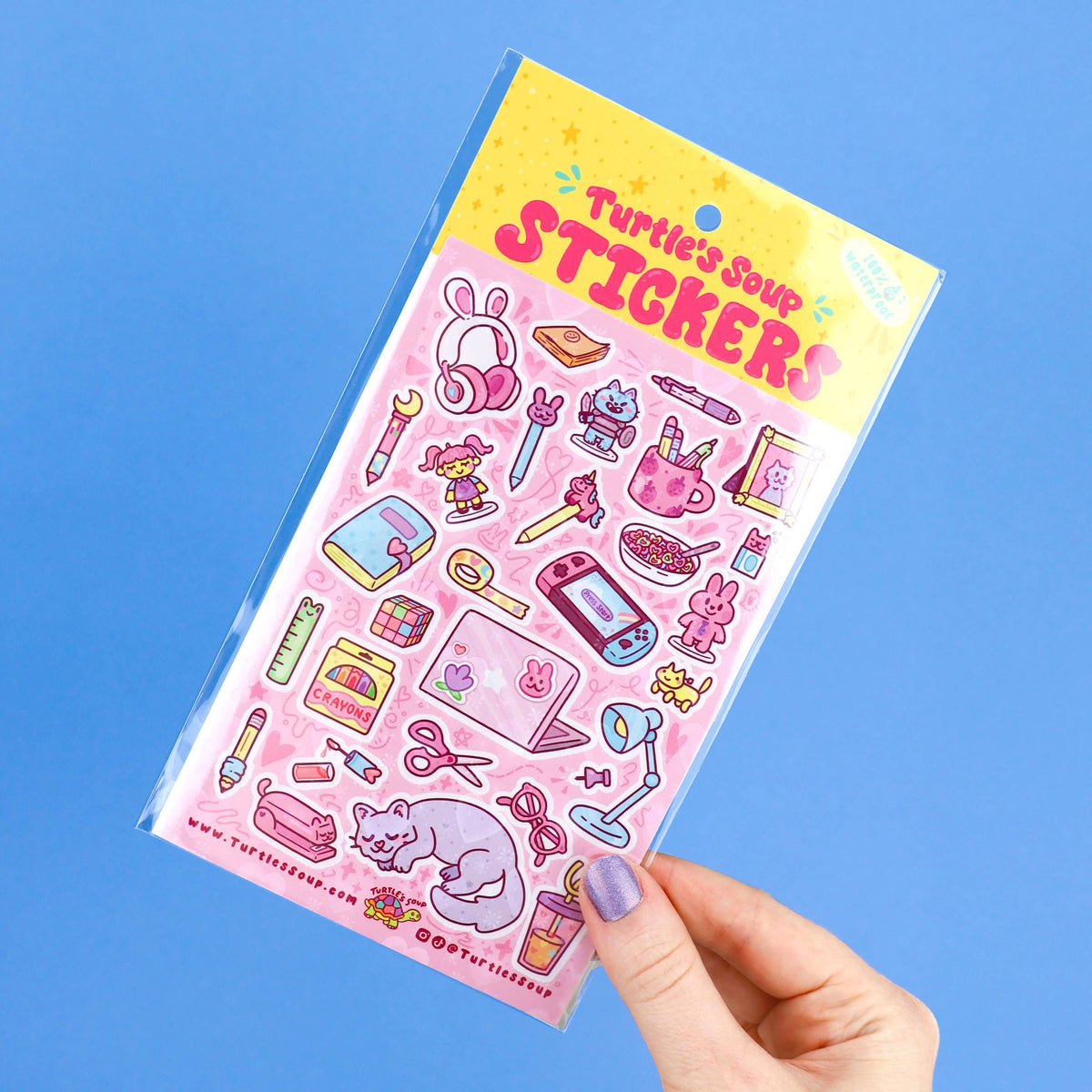 Hand holds a glitter sticker sheet with pink stationery designs and cute animal icons