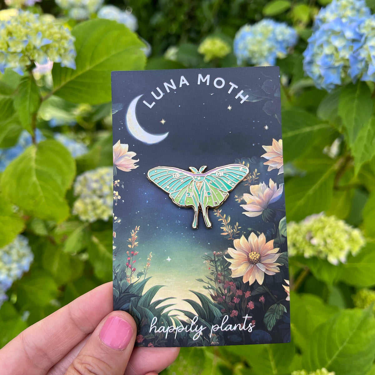 Luna moth pin product card held in hand, with illustrated moth and Happy plants branding