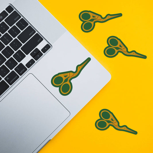 Green and gold stork-scissors vinyl waterproof stickers, multiple on laptop