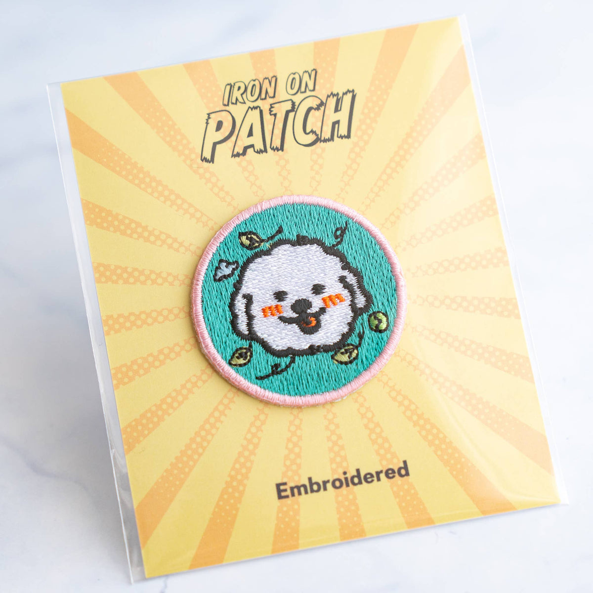 Round embroidered dog iron-on patch with gray dog face on teal with hearts