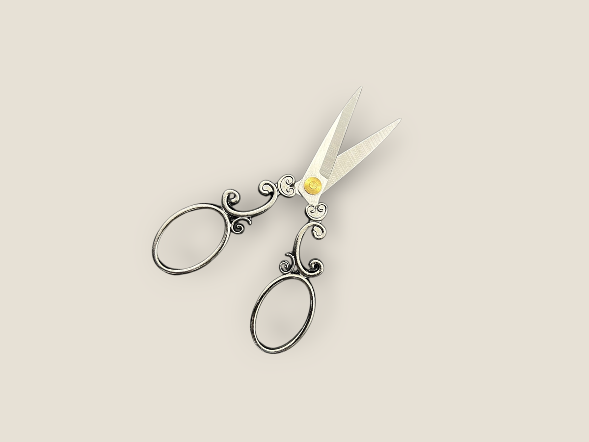 Arabesque scissors angled view with scrollwork handles, oval finger loops, and gold center charm