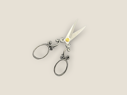 Arabesque scissors angled view with scrollwork handles, oval finger loops, and gold center charm